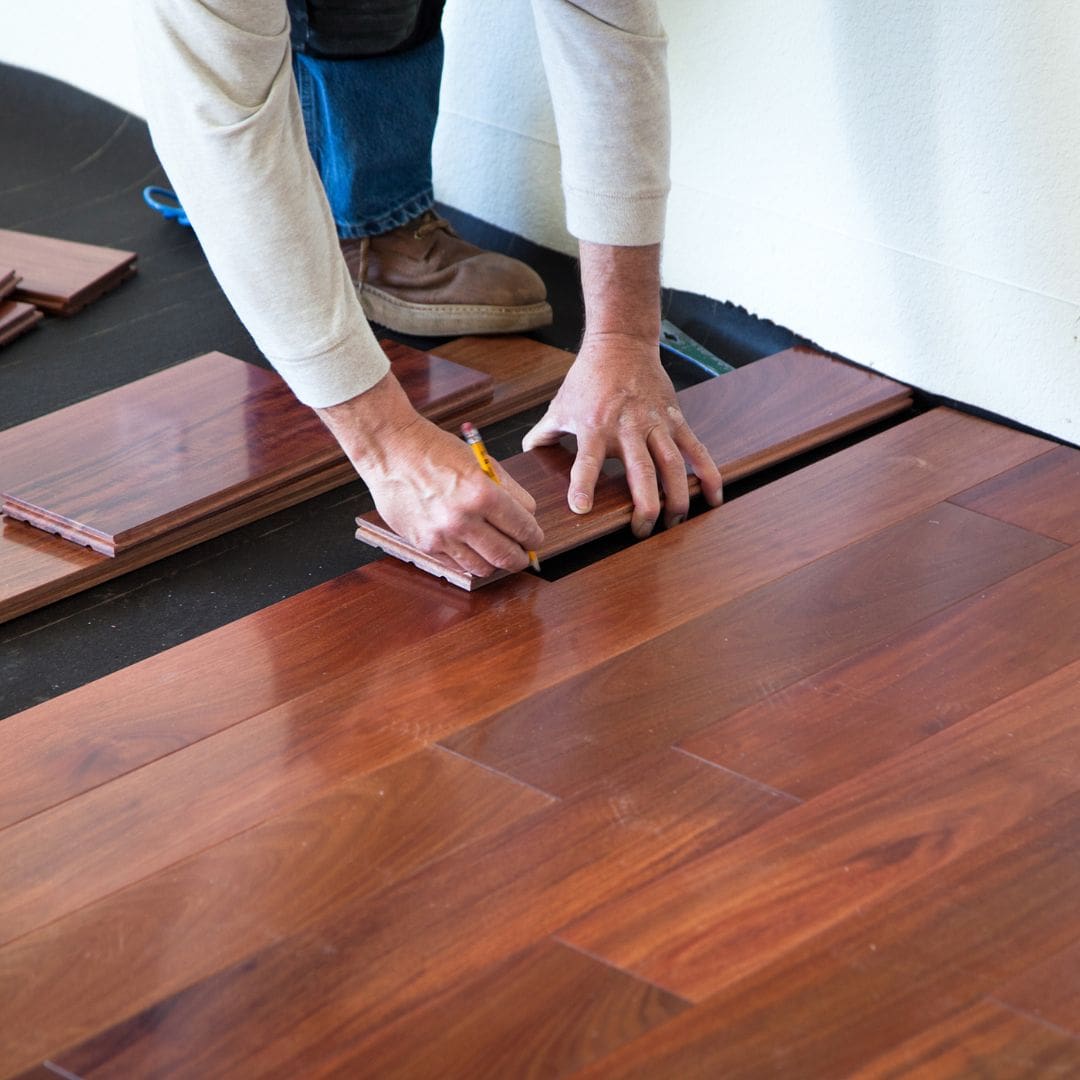 Worker marking and fitting hardwood floor planks